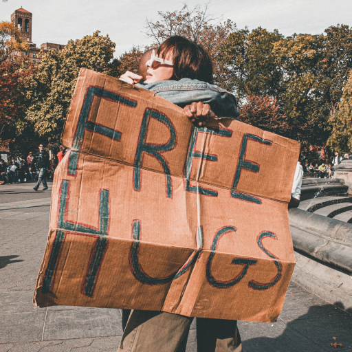 Man and woman hugging with Free Hugs Sign